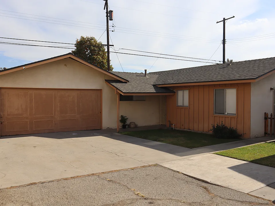 Front of house with attached garage t the end of a long, private driveway.