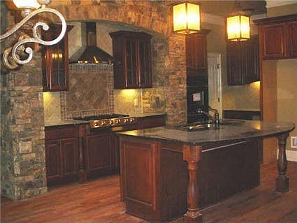 Kitchen with stone arch, custom cabinets, tile backsplash and eat-in island.
