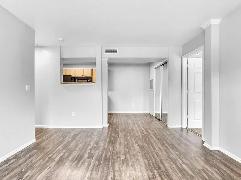 Modern open-plan apartment with elegant flooring, bright neutral walls, and a glimpse into a cozy kitchen area. Modern open-plan apartment with elegant flooring, bright neutral walls, and a glimpse into a cozy kitchen area.
