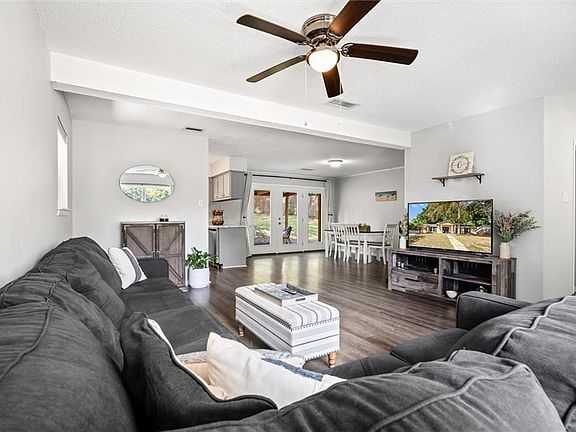 Living room with a textured ceiling, dark hardwood / wood-style flooring, french doors, ceiling fan, and beamed ceiling