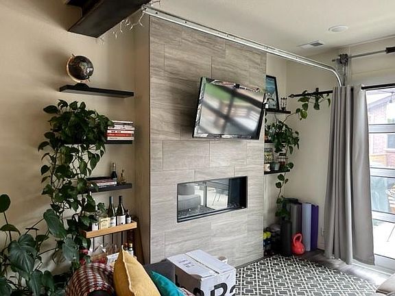 Actual photo of living room includes shelving, curtains and TV mount