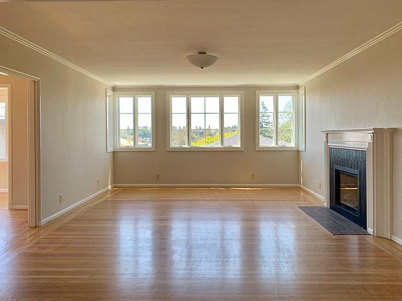 Living room with gas insert fireplace and brand new view windows overlooking backyard and Oakland hills