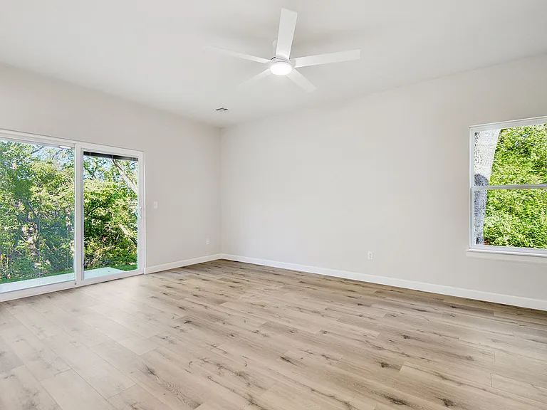 Living room looks out to mature trees and a creek right behind the duplex.