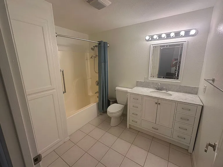 Bathroom with tub and shower. Vanity with marble top, tile floor and linen closet