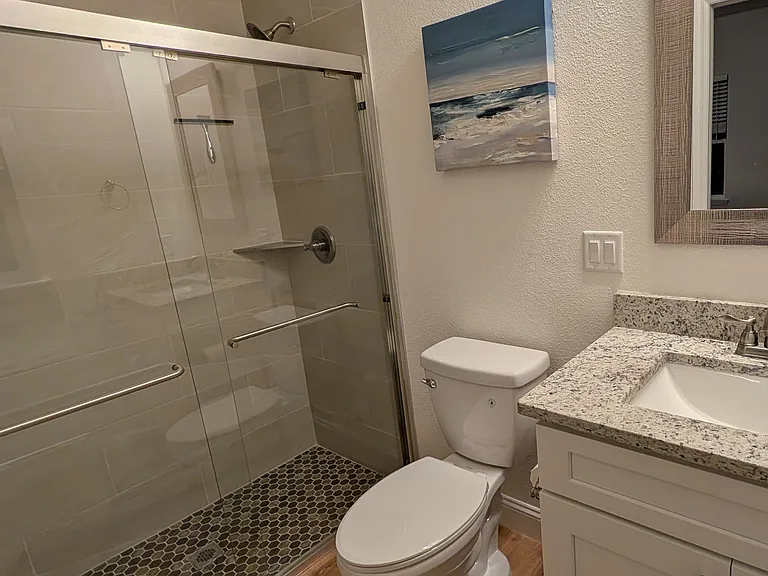 Spacious master bath with large walk-in shower, glass sliding door, and granite countertops.