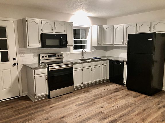 Contemporary eat-in kitchen featuring black appliances, granite counters, dishwasher, refrigerator, stove and built-in microwave. Walk out to the deck directly for grilling or relaxing!