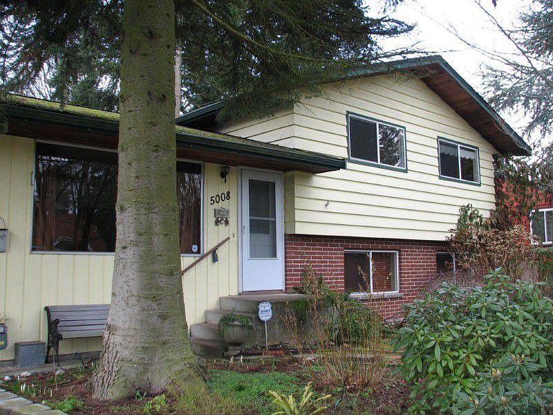 front of home with mature landscape.