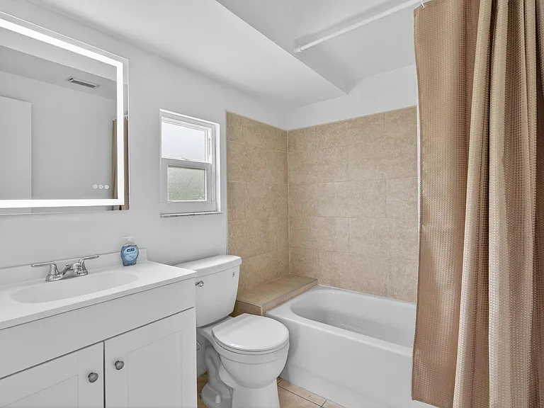 Full bathroom with a tub/shower combo, large vanity with mirror, and a window for ventilation and natural light.