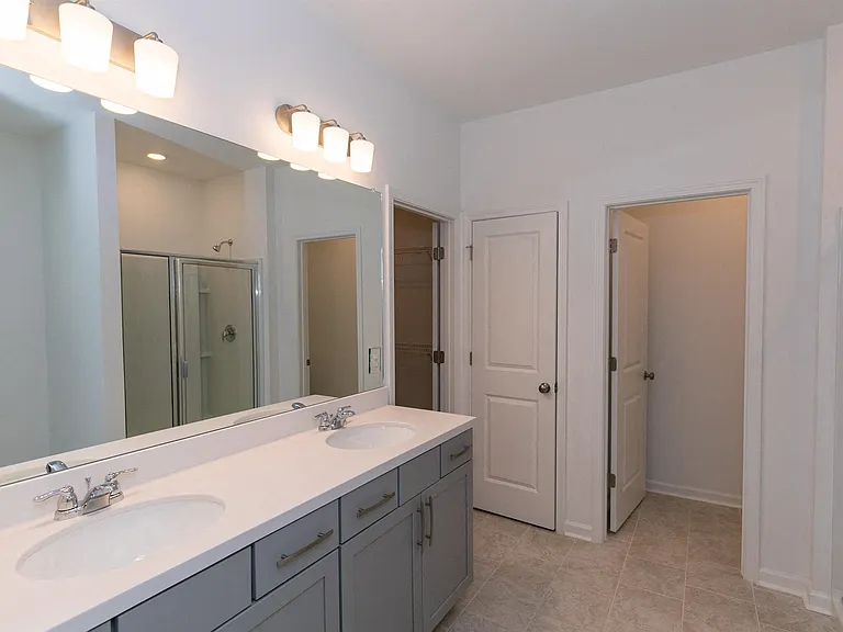 Primary bathroom with double vanity, walk-in shower and walk-in closet.