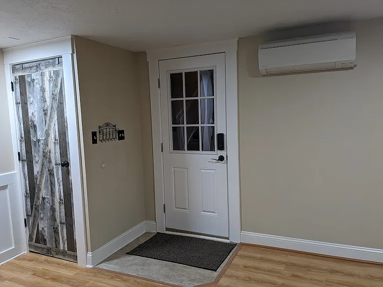 Coat closet and entrance door near alley with mini split.
