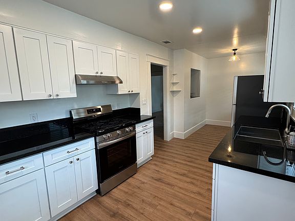Remodeled kitchen with white cabinets, black granite countertops