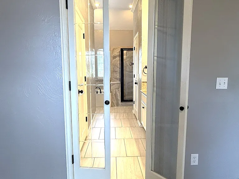 As you enter the master bathroom through the French doors, a jetted tub sits next to the shower. His and her closets located on right and left after you enter the primary master suite bathroom.