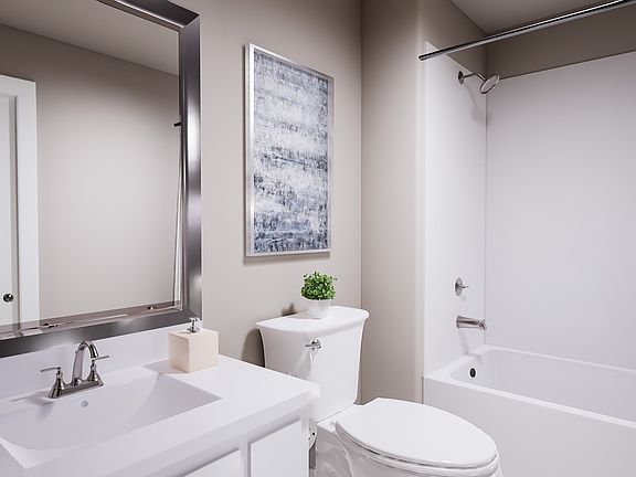 A modern, minimalist bathroom with a white vanity, toilet, and framed artwork on the wall, creating