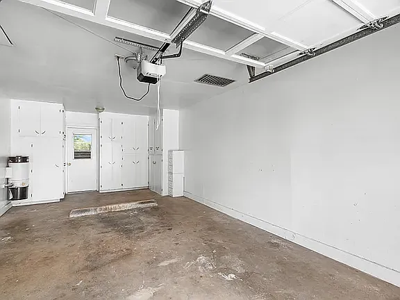 View of inside of the garage with lots of storage cabinets and door into Utility Room.