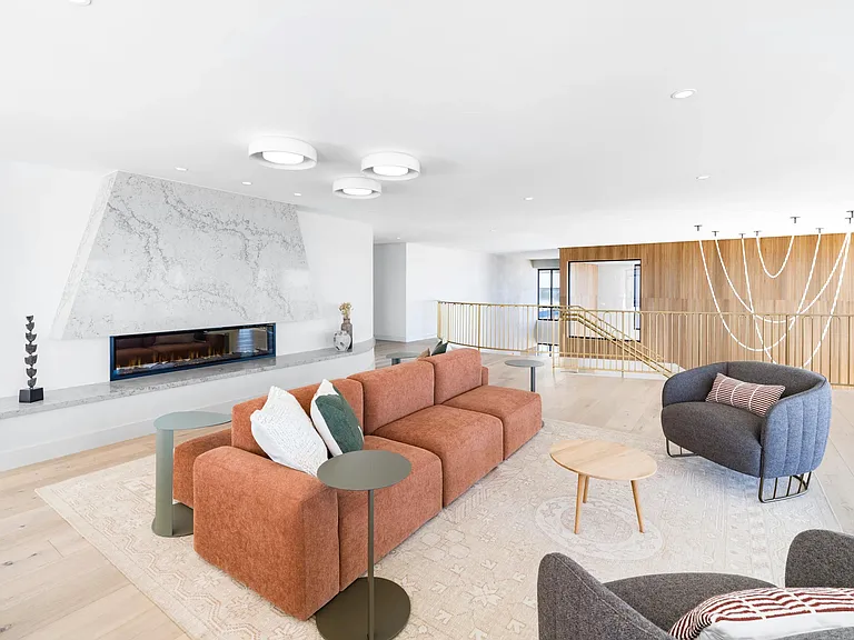 A light-filled resident lounge with statement fireplace, inviting seating, and space to relax or connect.