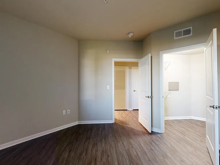 Spacious apartment bedroom with large closet and wood-style flooring.
