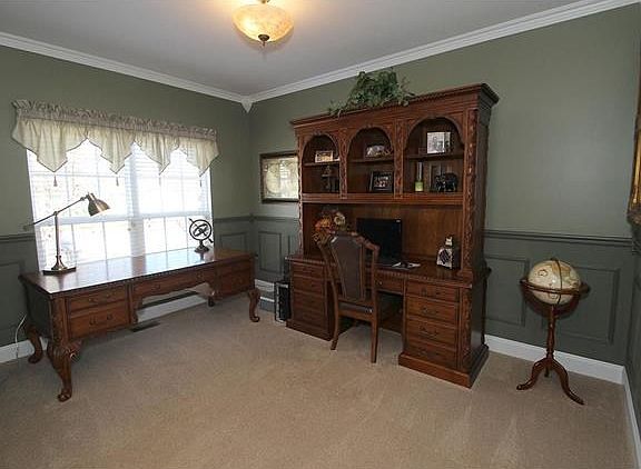 Inviting den with crown molding and wainscoating.