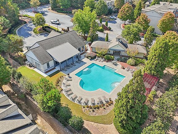 Aerial view of a luxurious residential complex featuring a sparkling swimming pool, lush greenery, and stylish modern buildings, perfect for relaxation and leisure.