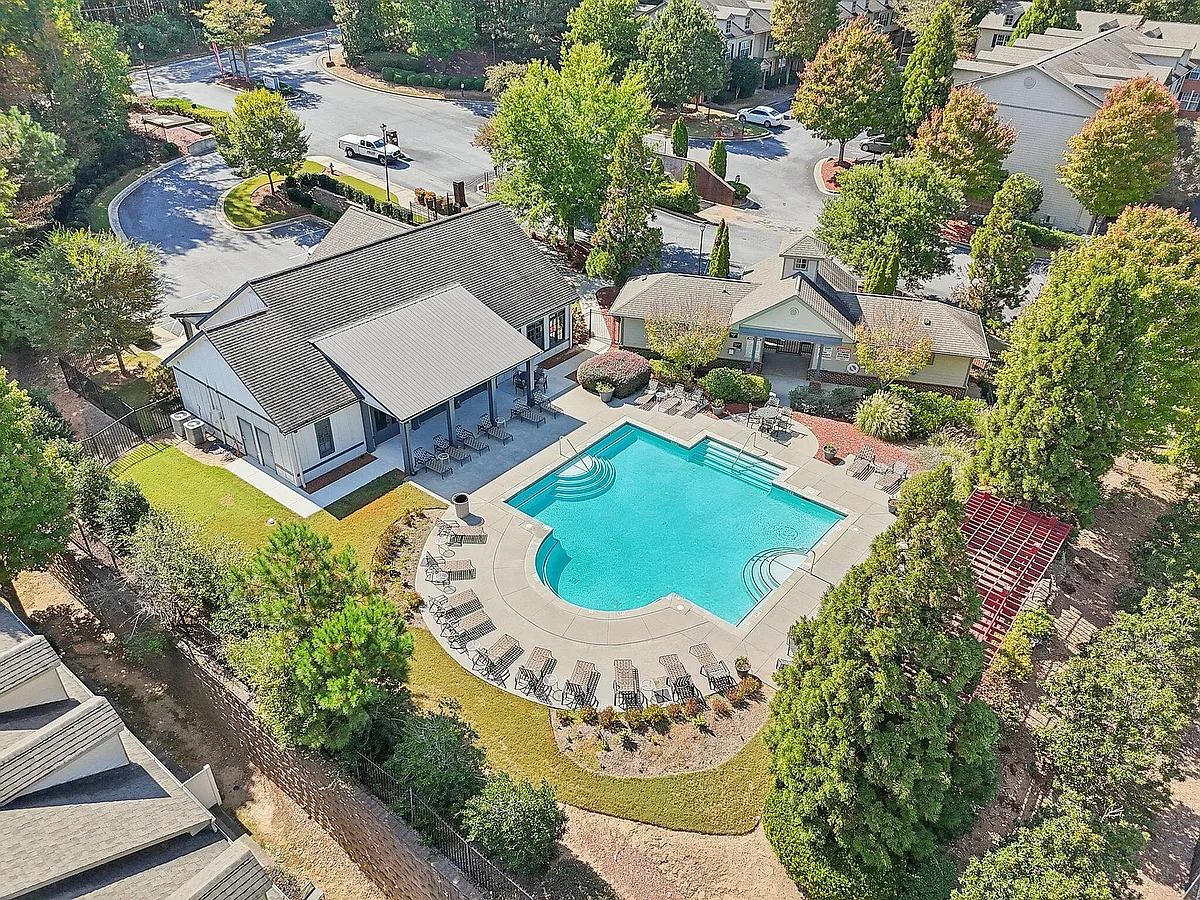 Aerial view of a luxurious residential complex featuring a sparkling swimming pool, lush greenery, and stylish modern buildings, perfect for relaxation and leisure. - Redwine Creek