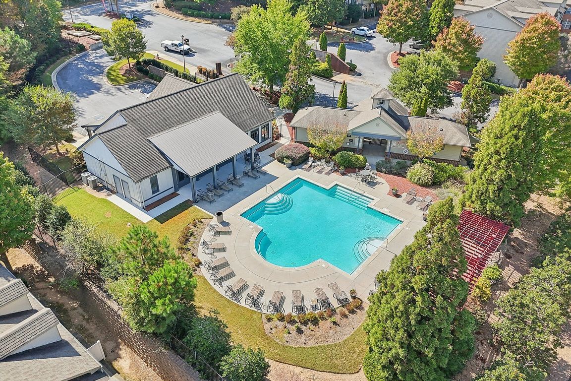 Aerial view of a luxurious residential complex featuring a sparkling swimming pool, lush greenery, and stylish modern buildings, perfect for relaxation and leisure.