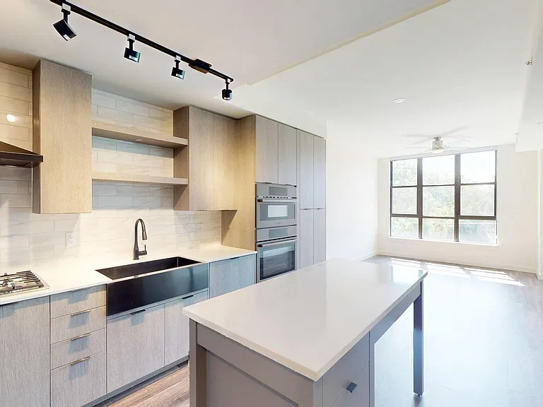 Apartment kitchen with stainless steel appliances, light counters, and wood style floor.