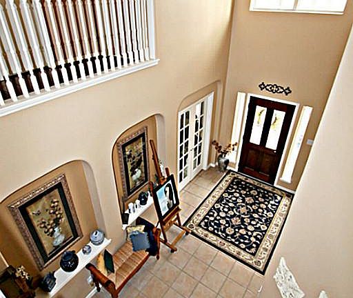 OPEN THE DOOR TO THE SOARING FOYER WITH TILE FLOORS, ART NICHES, DOUBLE STAIRCASE WITH HARDWOODS, AND A LOVELY CHANDELIER
