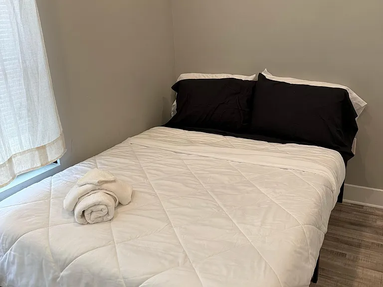 Private bedroom featuring a full-size bed, neutral walls, and a window with curtains for natural light and privacy.