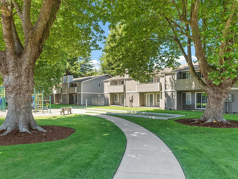Lush green spaces with shaded walkways and playground access.
