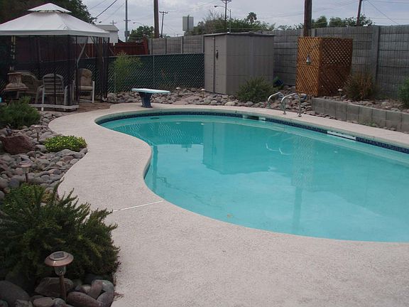 professionally landscaped fenced in pool, with flagstone patio & storage shed