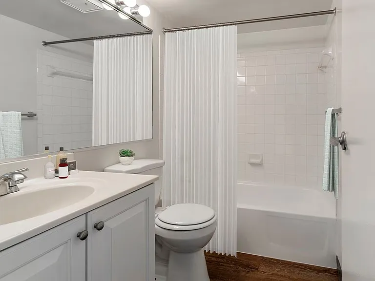 Renovated Package I bath white white cabinetry and hard surface flooring