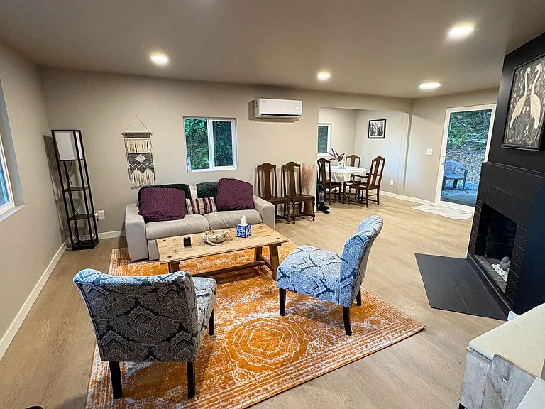 Open-concept living area with recessed lighting, seating arrangement, and adjoining dining space, plus a fireplace and patio