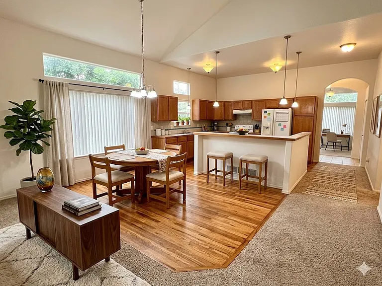 AI decorated view of dining area, bar, and kitchen from the living room. NOTE: Home is unfurnished.