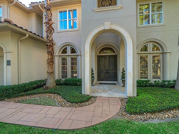 Beautiful stucco and tile roof elevation and grand walkway with perfect manicured landscaping leading up to the front door.