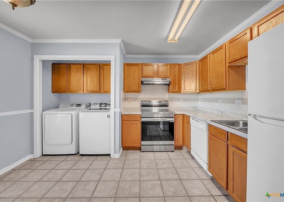 The kitchen area comes with a refrigerator, dishwasher, oven, stove, washer, and dryer. There is also plenty of room for a dining table in the space to the left of the picture.