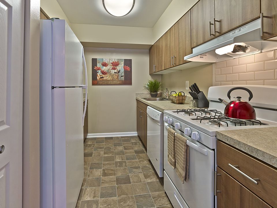 Stylish renovated kitchen at Haynes Run Apartments featuring wood cabinetry, gas cooking, a tile backsplash, and updated countertops for a modern living experience.