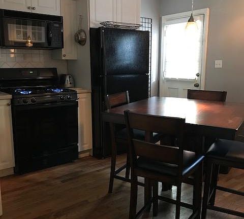 View of kitchen, gas stove and back entry from the living ro