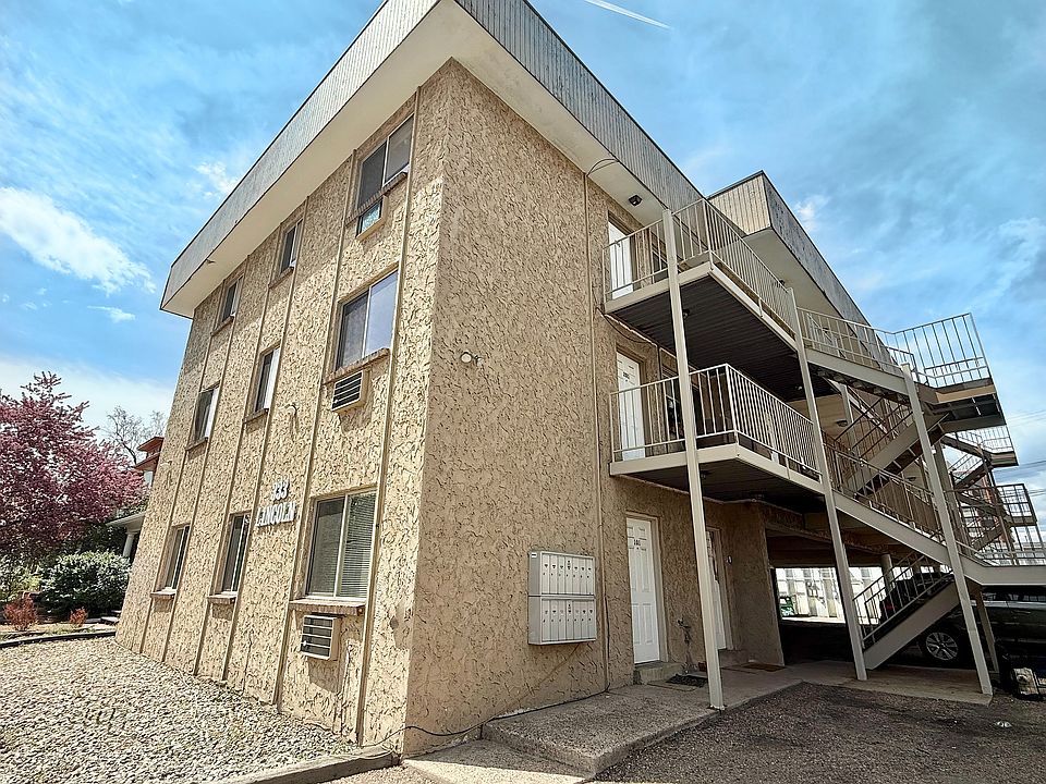 Charming three-story apartment building with modern staircases and textured exterior under a clear blue sky.