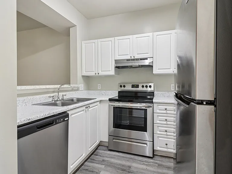 Modern kitchen with sleek stainless steel appliances, elegant white cabinetry, and polished countertops.