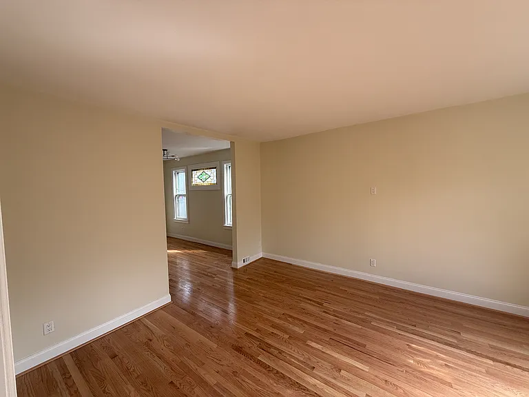 Sunny wide open living room with lovely leaded glass windows that flood the room with light. Brand new solid wood floors.