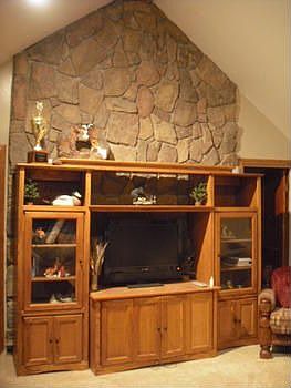 The living room features a vaulted ceiling, recess lighting, and a unique stone wall feature, this i