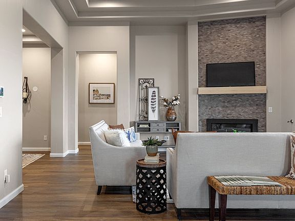 Gathering space with corner fireplace with stone and a decorative tray ceiling.