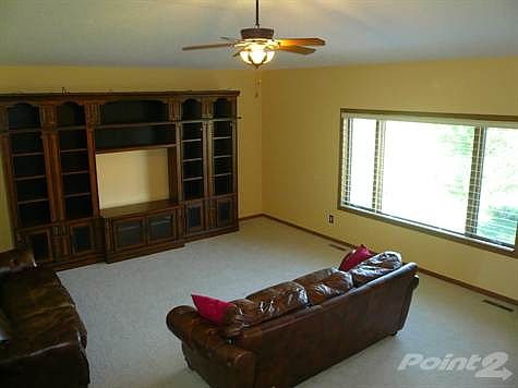 Open floor plan, spacious living room with large windows overlooking nature preserve, ceiling fan and light, neutral carpet