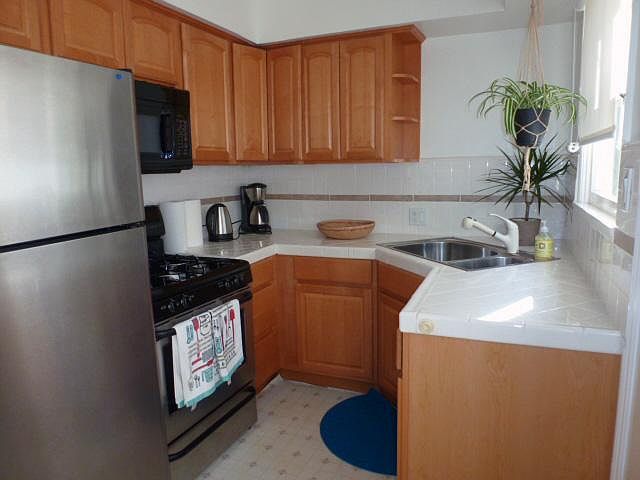 Updated kitchen includes a stainless steel fridge, stove, and microwave package.
