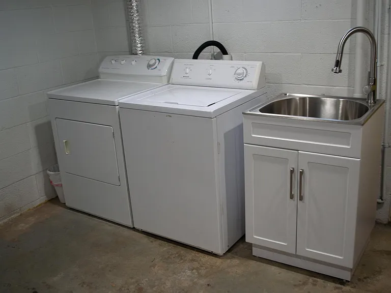 Washer, dryer and utility sink in basement.