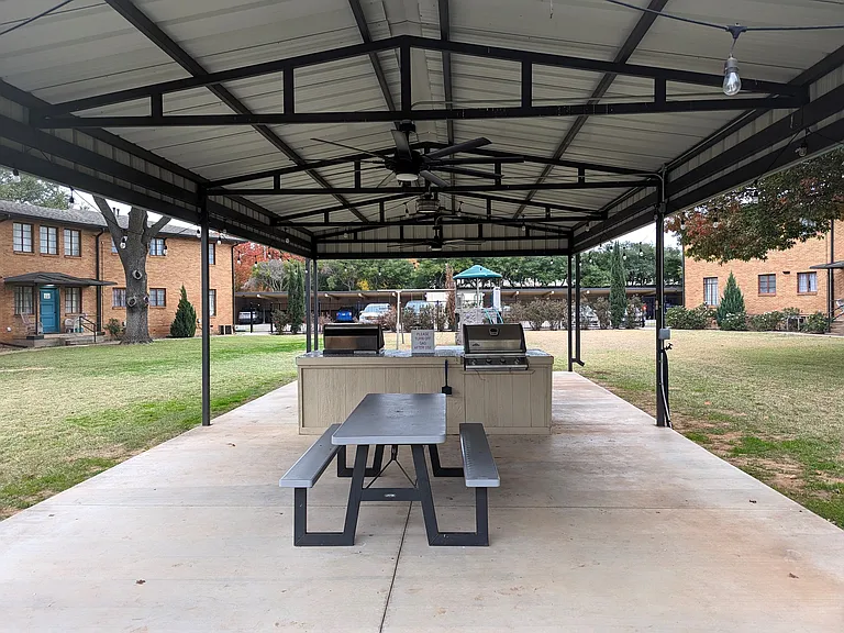 Covered outdoor gathering area with picnic seating, grills, and shared community space perfect for relaxing, dining, and enjoying the property.