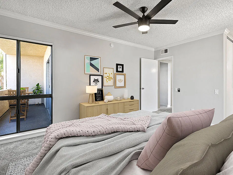 Carpeted bedroom with ceiling fan and natural light from adjacent patio.