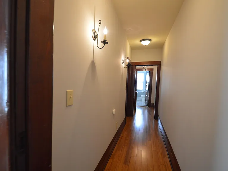 Hallway between two bedrooms with bamboo floors and updated light fixtures.