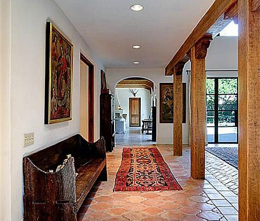 The gallery aligns on a single axis and stretches from the foyer through the center of the house allowing this stunning interior vista. Rustic support beams and herringbone-pattern Saltillo tile floor announce the dining room at right.