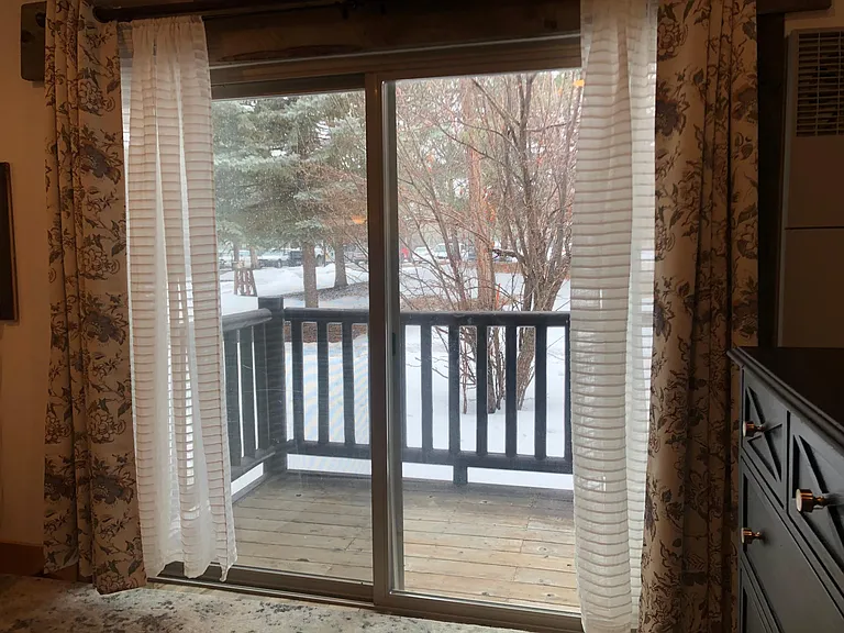 The patio faces a green space with an apple tree that blooms pink in summer. Room-darkening drapes, plus sheers.