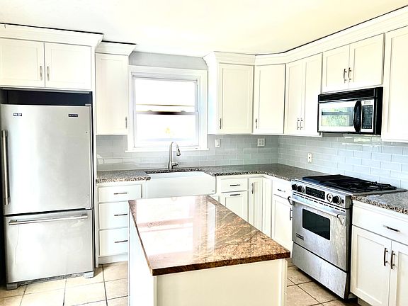 Post-Renovation (but pre-cleaning) Kitchen showing white cabinets and white glass backsplash.